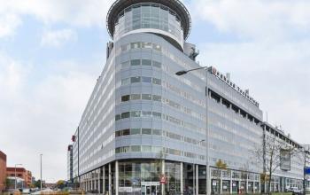 Modern kantoorpand aan de Regulusweg 11 in Voorburg met meerdere verdiepingen glasgevels en logo's van bedrijven. Ideaal voor bedrijven die kantoorruimte willen huren op een gunstige locatie.