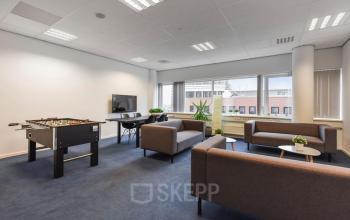 Kantoorruimte te huur op Regulusweg 11, Voorburg met moderne zitplaatsen, een tafelvoetbaltafel en stijlvol meubilair, ideaal voor informele bijeenkomsten.