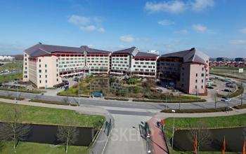 Buitenaanzicht van een groot kantoorpand gelegen aan Loire 104 - 206 in Voorburg met parkeerplaats ervoor.