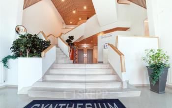 Ingang van kantoorpand op Loire 104 - 206, Voorburg. Fris en ruim design met planten en houten accenten, ideaal voor ontvangst.