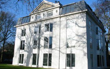 Buitenkant van kantoorpand Van der Oudermeulenlaan 1 in Wassenaar, modern wit gebouw met glazen ramen in een groene omgeving.