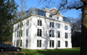 Exterieur van het kantoorpand aan Van der Oudermeulenlaan 1, Wassenaar. Modern wit gebouw met grote ramen en omliggende groene tuin.