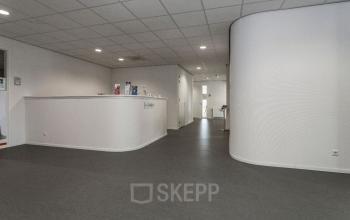 Heldere entree van het kantoorpand aan de Kerkstraat 1 in Westervoort, ideaal voor kantoorruimte huren. Het interieur is ruim met strakke wanden en een grijze vloer.
