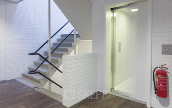 Modern ingerichte entree van kantoorpand aan Pompmolenlaan 9 in Woerden met trap en lift voor toegankelijk kantoor huren.