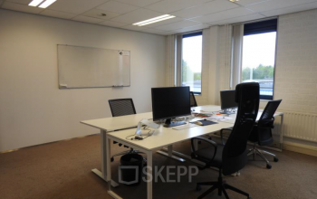 Kantoorruimte huren in kantoorpand gelegen aan Pompmolenlaan 9, Woerden, met werkplekken aan bureaus, computerschermen en stoelen bij de ramen.