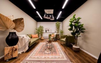Stijlvol ingerichte lounge in het kantoorpand op Pelmolenlaan 16, Woerden. Verschillende zitplaatsen en planten creëren een uitnodigende sfeer voor huren van kantoorruimte.