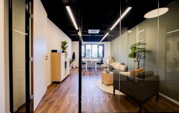 Moderne kantoorruimte huren op Pelmolenlaan 16, Woerden. Stijlvol ingericht met houten vloeren, glazen wanden en planten. Ideaal voor zakelijke meetings of teamwerk.