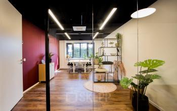 Moderne kantoorruimte aan Pelmolenlaan 16 in Woerden, ingericht met houten vloer, planten, en glazen wanden. Ideaal voor wie kantoor wil huren met frisse, professionele uitstraling.