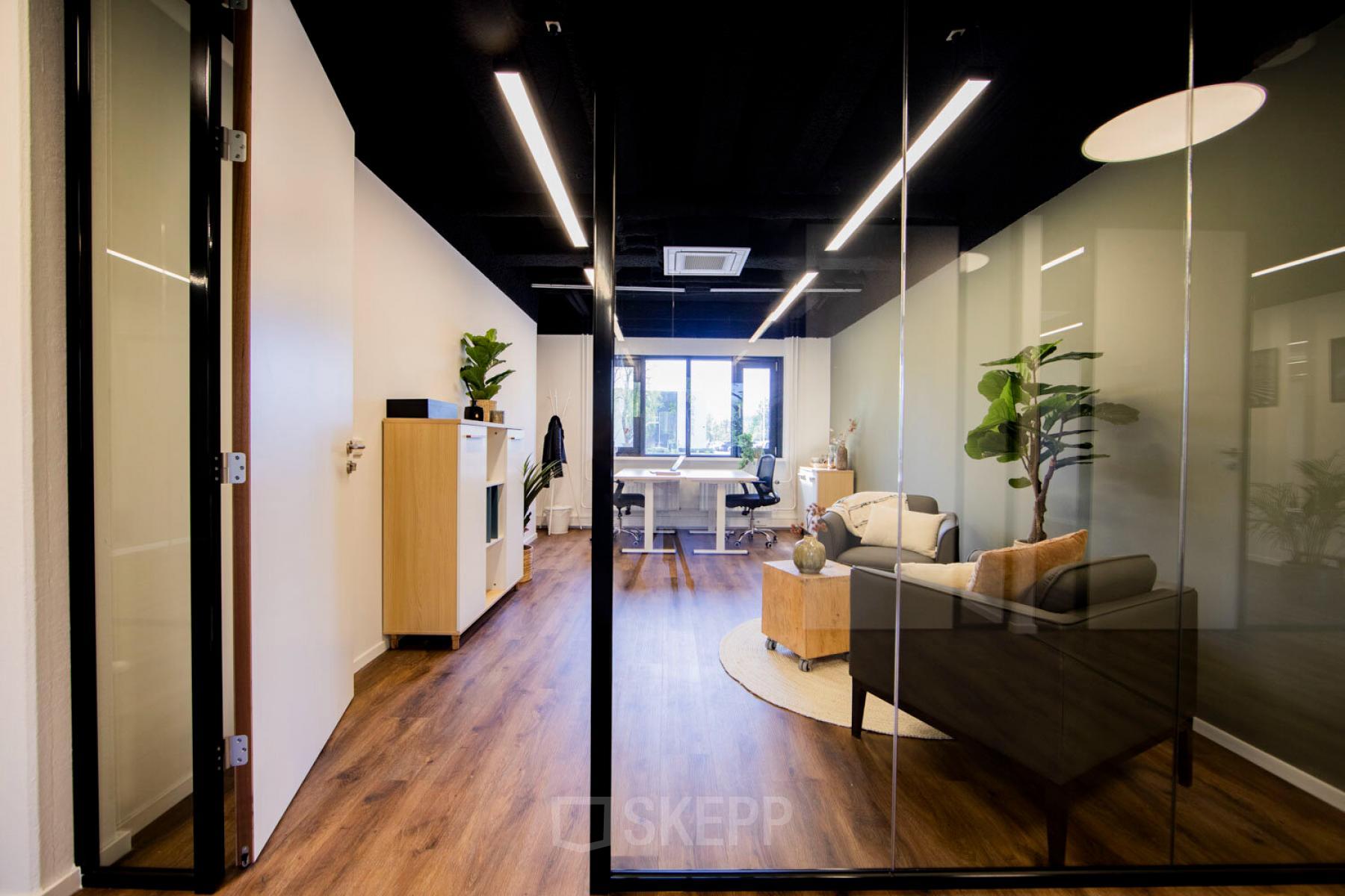 Moderne kantoorruimte huren op Pelmolenlaan 16, Woerden. Stijlvol ingericht met houten vloeren, glazen wanden en planten. Ideaal voor zakelijke meetings of teamwerk.