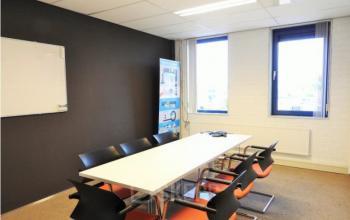 Kantoorruimte huren in Woerden bij Pompmolenlaan 9 met een vergadertafel en stoelen, geschikt voor zakelijke overleggen in een helder verlichte ruimte.