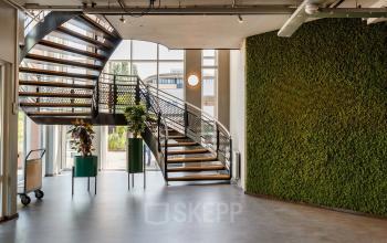 Lichte, moderne kantoorruimte op Vijzelmolenlaan 9 in Woerden, ideaal voor zakelijke bijeenkomsten. Eco-vriendelijke muurdecoratie en open trap versterken de uitstraling van het kantoorpand. Overweeg hier uw kantoorruimte te huren.