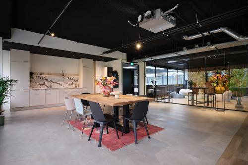 Stijlvolle kantoorruimte huren in Woerden, Vijzelmolenlaan 9. Moderne inrichting met een grote tafel, kleurrijke bloemen, en een ontspannende zithoek. Perfect voor zakelijke bijeenkomsten en informele vergaderingen.