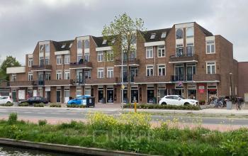 Buitenaanzicht van het kantoorpand aan Boerendijk 8 in Woerden met meerdere winkels op de begane grond en parkeermogelijkheden aan de voorzijde.
