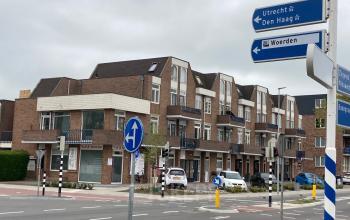Exterieur van een kantoorpand op Boerendijk 8 in Woerden, gelegen aan een druk kruispunt met verkeersborden richting Utrecht en Den Haag.