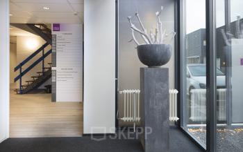 Ingang van het kantoorpand op Pompmolenlaan 26, Woerden met moderne kunst en grote raampartijen.