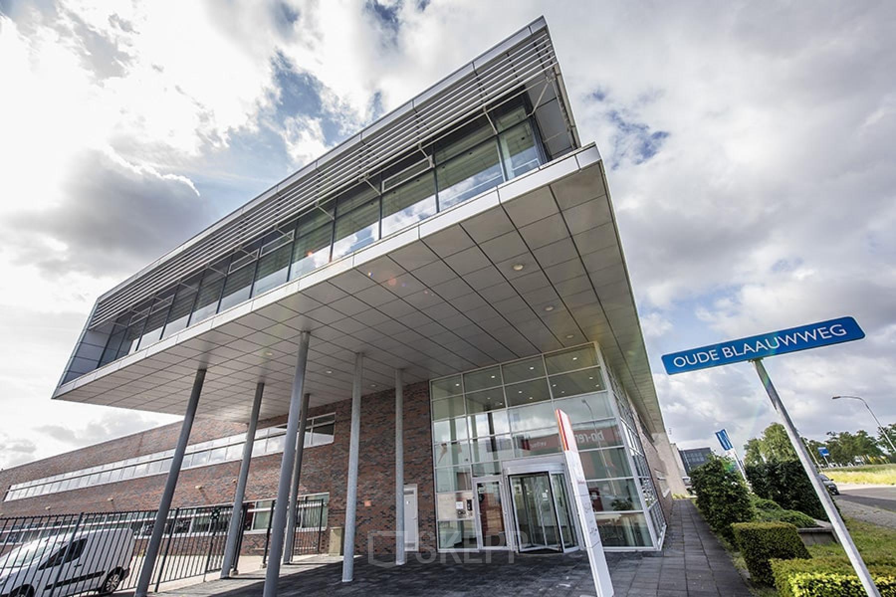 Uitzicht op het moderne kantoorpand aan Oude Blaauwweg 5, Wormerveer, ideaal om te huren. Het pand heeft een stijlvolle glazen voorgevel en een uitnodigende entree.