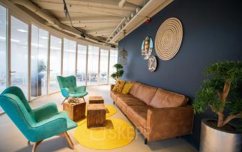 Een sfeervolle en gemeubileerde kantoorruimte in Zoetermeer, Boerhaavelaan 40, met een zithoek met stoelen, een bank, en decoratieve elementen. Ideaal voor vergaderingen of informele gesprekken. Perfect om als kantoorpand te huren.