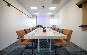 Vergaderruimte in kantoorpand op Boerhaavelaan 40, Zoetermeer. Grote tafel met comfortabele stoelen en presentatiescherm aanwezig.