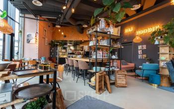 Modern ingerichte kantoorruimte met zitplekken, planten en een caféhoek in kantoorpand Boerhaavelaan 40, Zoetermeer. Ideale plek voor kantoorruimte huren met een creatieve sfeer.