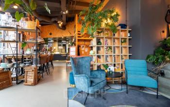Moderne kantoorruimte huren op Boerhaavelaan 40, Zoetermeer, met stijlvolle meubelen, open planken en plantdecoratie. Gezellige zithoek en bijpassend interieur. Ideaal voor zakelijke bijeenkomsten.