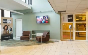 Ingang van een kantoorpand aan de Bredewater 26 in Zoetermeer met moderne fauteuils en een flatscreen aan de muur. Ideaal voor kantoorruimte huren.