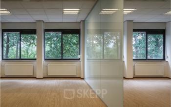 Lichte kantoorruimte te huur in Zoetermeer met grote ramen en glazen wand, ideaal voor kantoren. Het kantoorpand biedt een open en rustige werkomgeving met uitzicht op groen.