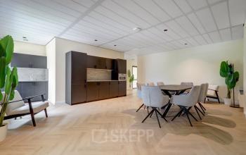 Gezellige kantoorruimte met houten vloer, modern meubilair en een grote tafel in Zoetermeer. Ideaal voor ondernemers die kantoorruimte willen huren op Edelgasstraat 101.