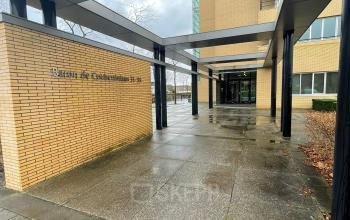 Entree van het kantoorpand aan de Baron de Coubertinlaan 35 in Zoetermeer, met een overdekte ingang en bakstenen gevel. Ideaal om kantoorruimte te huren in een indrukwekkende zakelijke omgeving.