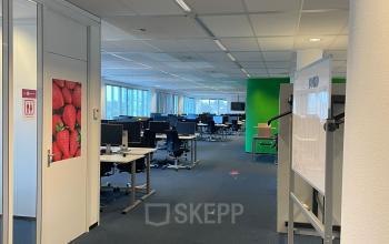 Een ruime kantooretage op Baron de Coubertinlaan 35, Zoetermeer, met meerdere bureaus en stoelen, ideaal voor het huren van kantoorruimte.