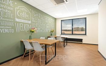Moderne vergaderruimte in kantoorpand op Stationsplein 4 in Zwijndrecht met een groot krijtbordmuur, vergadertafel en stoelen.