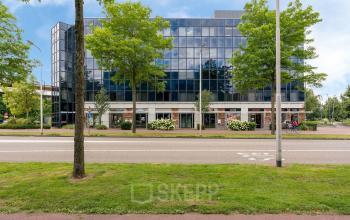 Modern kantoorpand aan Stationsplein 4 in Zwijndrecht met glazen gevel en groene omgeving, ideaal voor kantoorruimte huren.