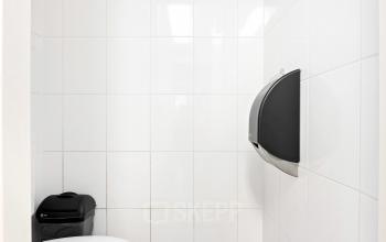 Stijlvolle, wit betegelde toiletruimte met zwarte vloer en moderne voorzieningen in kantoorpand op Stationsplein 4, Zwijndrecht.