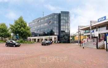 Zakelijk kantoorpand aan het Stationsplein 4 in Zwijndrecht met grote glazen gevel. Het biedt mogelijkheden voor kantoorruimte huren in een moderne omgeving. Buiten zijn geen personen te zien.