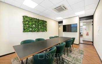 Moderne vergaderruimte in een kantoorpand op Stationsplein 4, Zwijndrecht, met groene accenten en comfortabele stoelen, ideaal voor kantoorruimte huren.