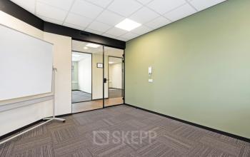 Leeg kantoorpand aan Stationsplein 4, Zwijndrecht, met modern interieur. Ideaal voor wie kantoorruimte wil huren. De ruimte heeft frisse groene accenten en voldoende licht.