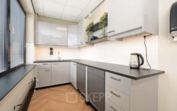 Moderne pantry met strakke kasten en voldoende ruimte, ideaal voor een korte pauze in het kantoorpand op Stationsplein 4, Zwijndrecht. Geschikt voor bedrijven die kantoorruimte huren.
