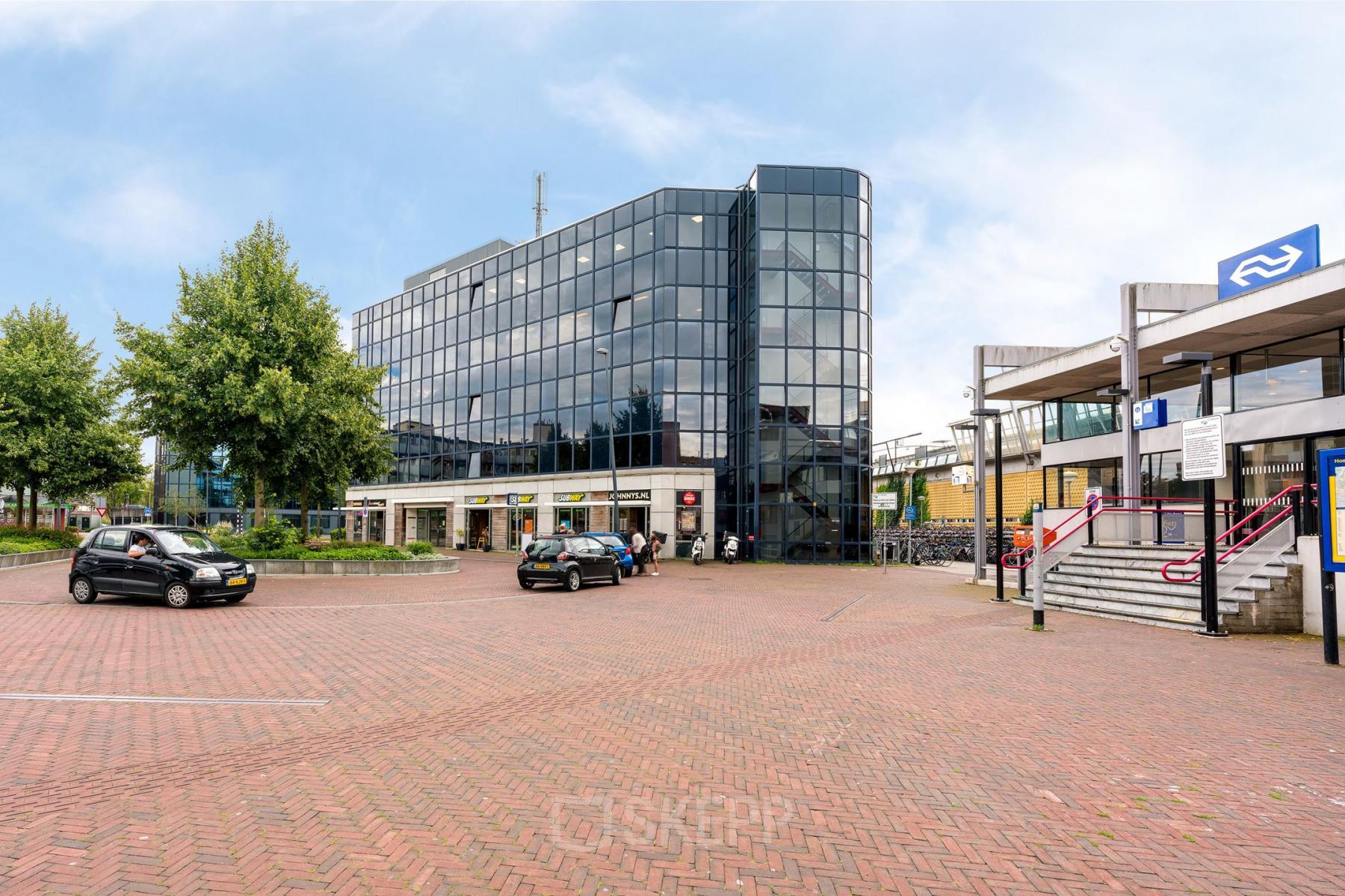 Zakelijk kantoorpand aan het Stationsplein 4 in Zwijndrecht met grote glazen gevel. Het biedt mogelijkheden voor kantoorruimte huren in een moderne omgeving. Buiten zijn geen personen te zien.