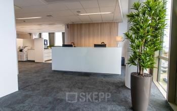 Moderne kantoorruimte met een stijlvolle receptiebalie, waar medewerkers zakelijke activiteiten uitvoeren. Ideaal voor wie kantoorruimte wil huren op een uitstekende locatie in Zwolle.