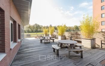 Terras met houten zitplekken en plantenbakken bij kantoorpand op Zuiderzeelaan 27-41, Zwolle, ideaal voor huur voor ontspanning en vergaderingen in de buitenlucht.