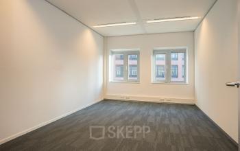 Ongebruikte kantoorruimte met twee ramen, lichte muren en tapijtvloer aan de Zuiderzeelaan 27-41, ideaal voor het inrichten van een nieuwe werkplek in Zwolle.