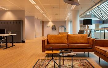 Moderne kantoorruimte op Zwartewaterallee 48 in Zwolle met stijlvolle leren banken, bijzettafels en een vloerkleed, ideaal voor informeel overleg of pauzes tijdens het huren van kantoor.
