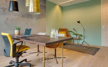 Moderne kantoorruimte huren op Zwartewaterallee 48 in Zwolle met stijlvol meubilair, vergadertafel en stoelen, groene planten en speelse verlichting.