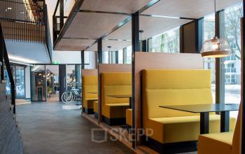 Modern kantoorpand aan Assendorperdijk 1, Zwolle, met gele zitnissen naast grote ramen, ideaal voor kantoorruimte huren.