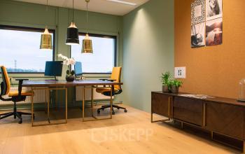 Stijlvolle kantoorruimte op Assendorperdijk 1, Zwolle met houten vloeren, moderne lampen en dubbele werkplekken met uitzicht naar buiten.