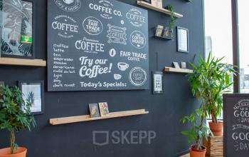 Stijlvolle kantoorlounge met zwarte muren, planten en speelse wanddecoraties op Assendorperdijk 1, Zwolle. Ideaal voor een creatieve werkplek om kantoren te huren.