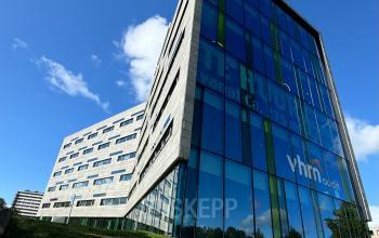 Modern kantoorpand gelegen aan Zwartewaterallee 56, Zwolle. Blauwe glaspanelen reflecteren de lucht.