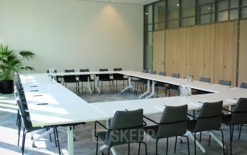 Lichte vergaderruimte huren in kantoorpand op Zwartewaterallee 56, Zwolle, met moderne tafels en stoelen rondom in een U-opstelling.