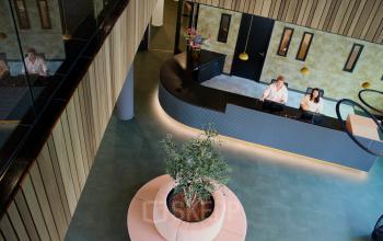 Een kantoorpand aan de Zwartewaterallee 56 in Zwolle met receptie en plantenbak, personeel achter de balie is aan het werk.