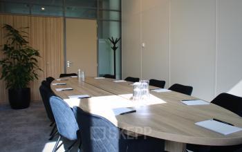 Vergaderruimte in het kantoorpand op Zwartewaterallee 56 in Zwolle, met een grote houten tafel omringd door stoelen en notitieblokken.