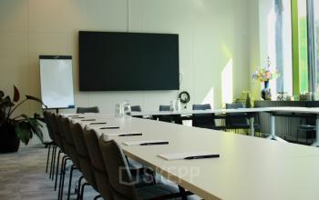 Kantoorruimte huren op Zwartewaterallee 56, Zwolle; vergaderruimte met conferentietafel, stoelen, flipover en groot scherm, kantoorpand heeft grote ramen en veel daglicht.